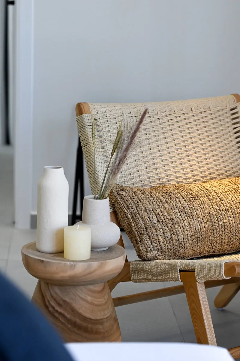 A woven armchair and a side table with candles