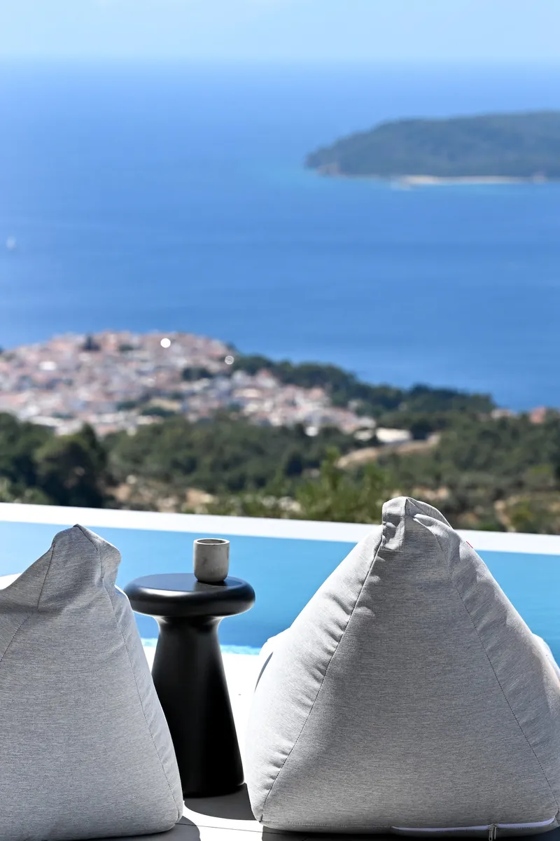 Two bean bags and a side table by the pool, Skiathos Town and the sea beyond