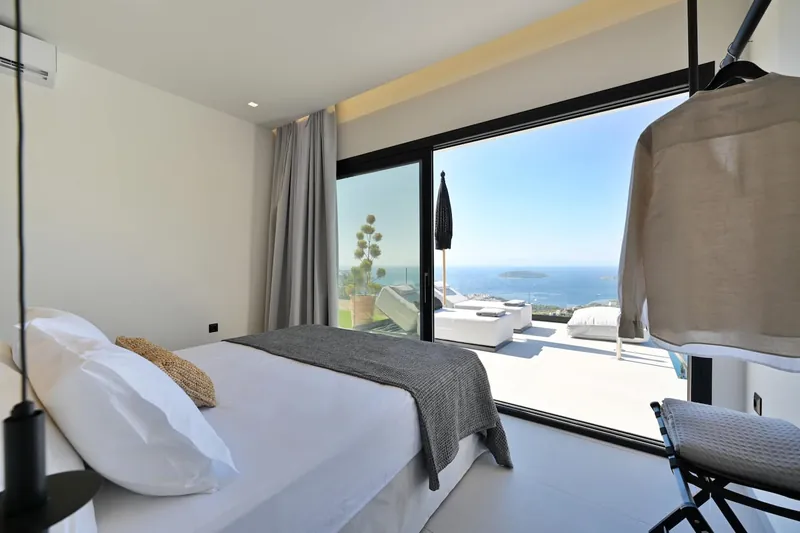 The bedroom’s glass doors open to the sea view