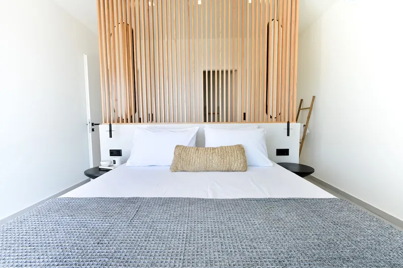 The double bed in front of the oak-slat wall