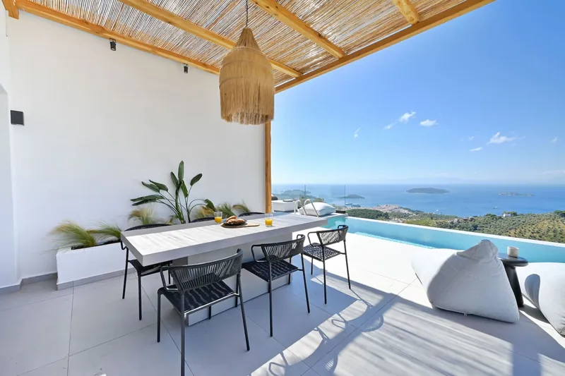 The dining table under the pergola, with the pool and the sea beside it