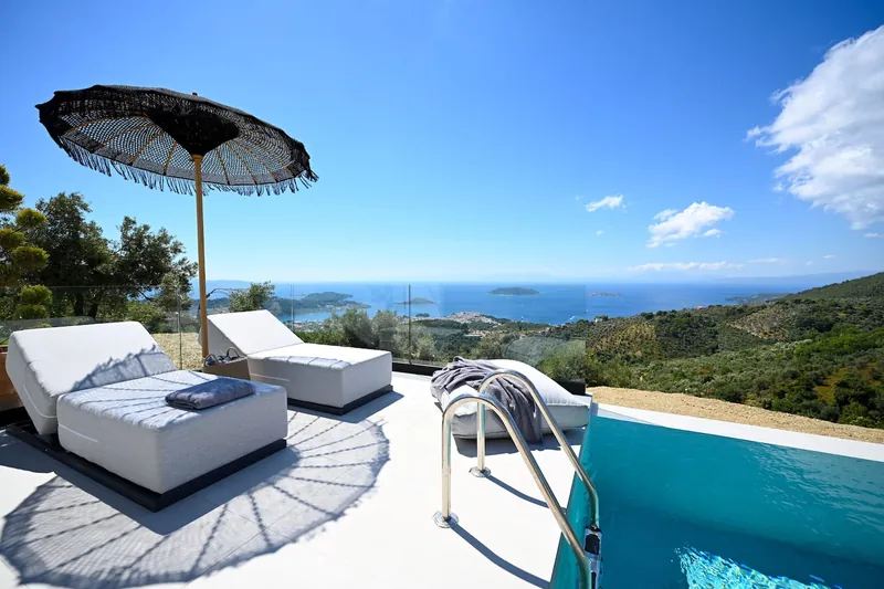 Two sun loungers under a fringed parasol beside the pool