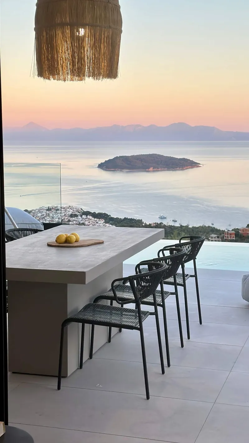 The terrace bar at first light, under a rattan lamp, an islet on a pink sea