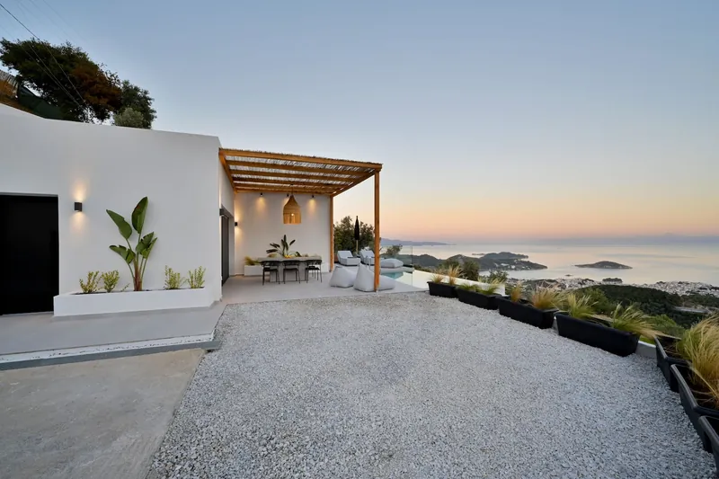 The villa, its pergola and the gravel yard at sunset